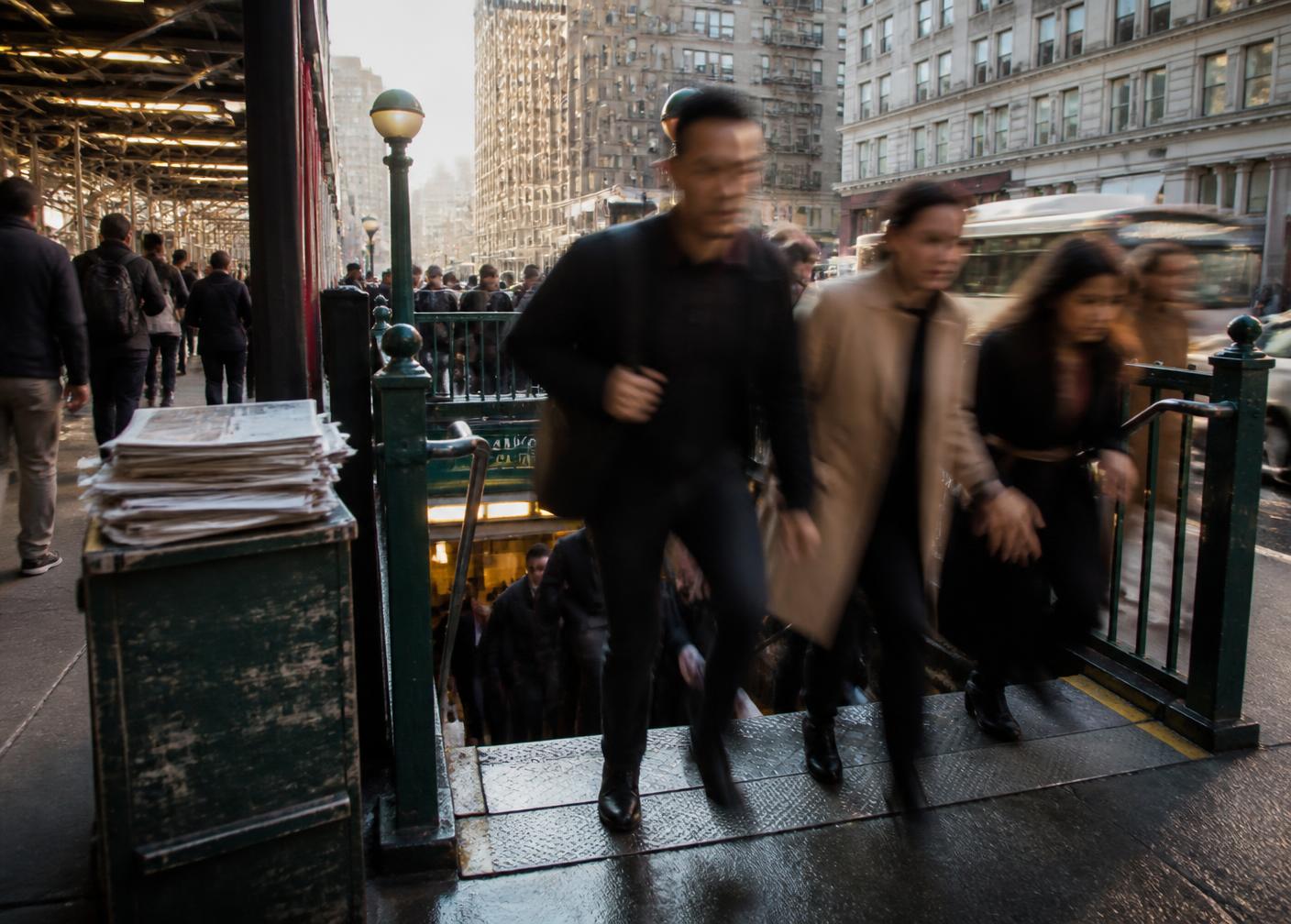 Commuters rushing up a subway staircase in motion blur