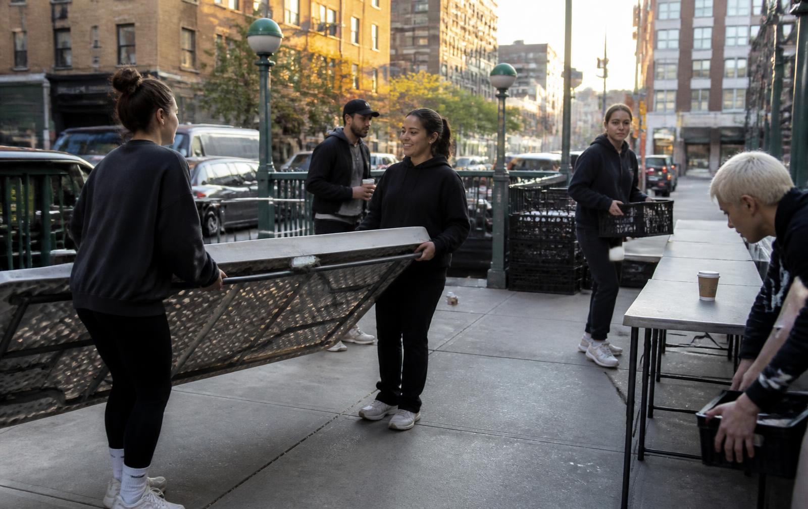 Team carrying folding tables to an event beside a subway entrance